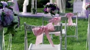 白色的椅子，粉<strong>红色</strong>的蝴蝶结在<strong>户外婚礼</strong>的维林克。 结婚装饰品。